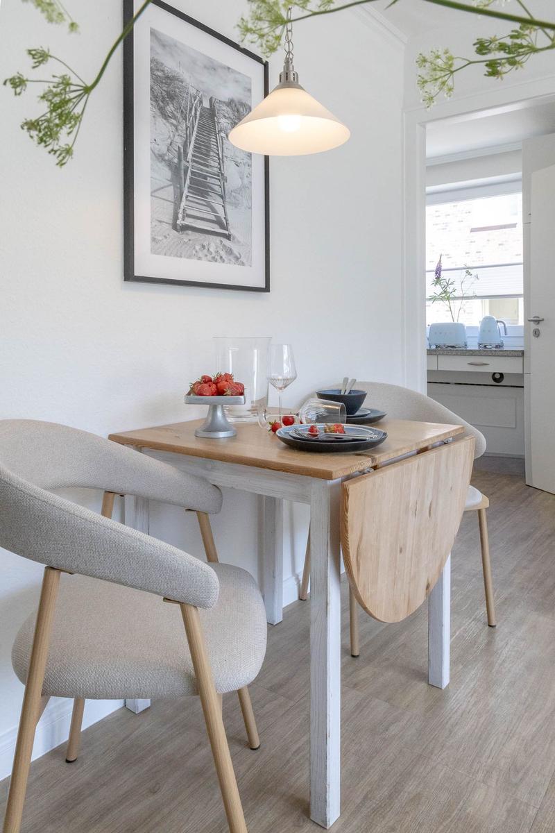 Esstisch mit vier Stühlen, Wandbild und Hängelampe im Essbereich.