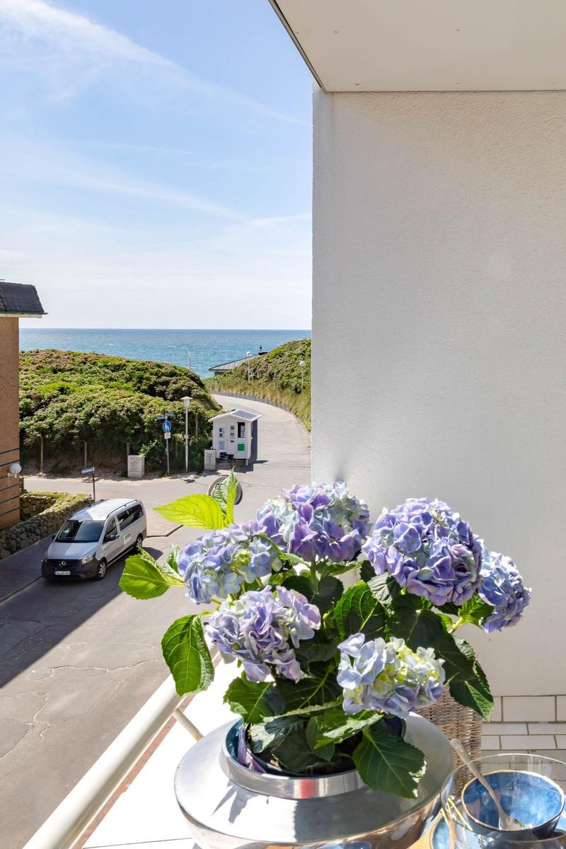 Blumenstrauß auf Balkon mit Blick auf Straße und Meer.
