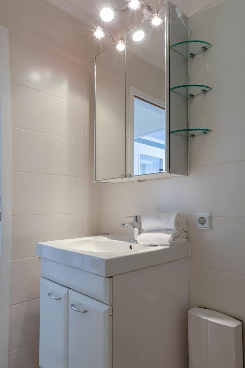Badezimmer mit Waschbecken, Spiegelschrank und Glasregalen.