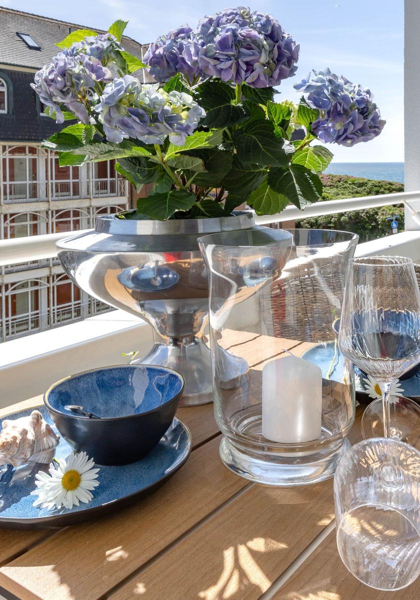 Terrasse mit Blumen, Tischdekoration und Meerblick.