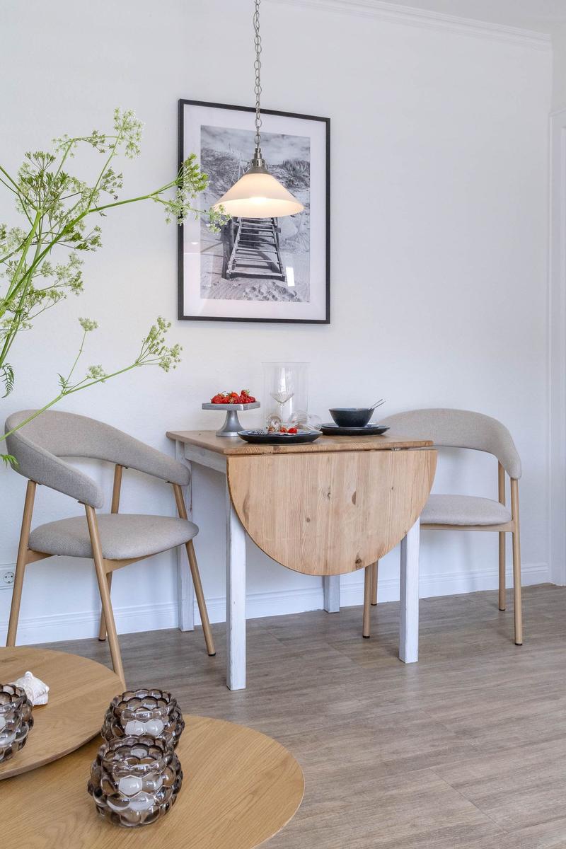 Esstisch mit zwei Stühlen, Wandbild und Pendelleuchte.
