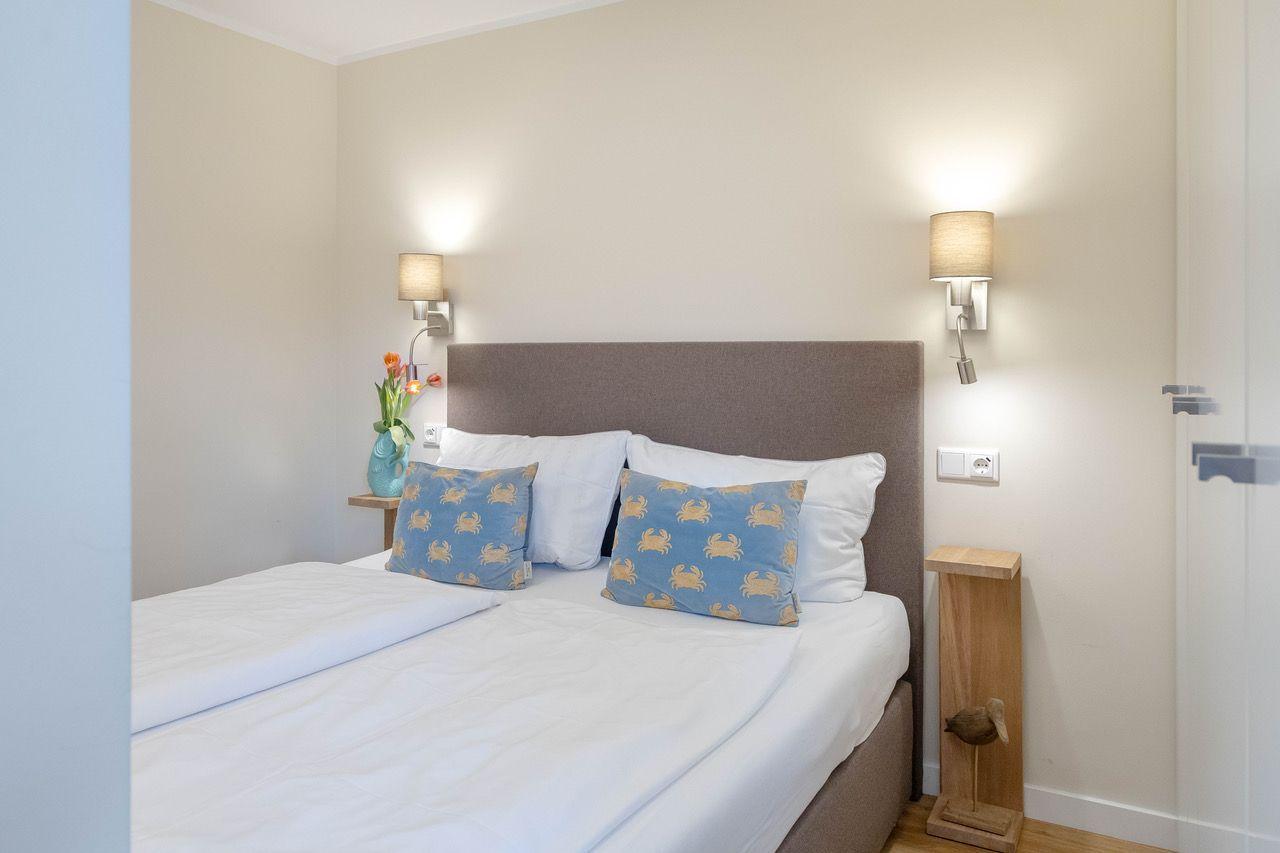 Schlafzimmer mit Bett, Kissen und Wandlampen.