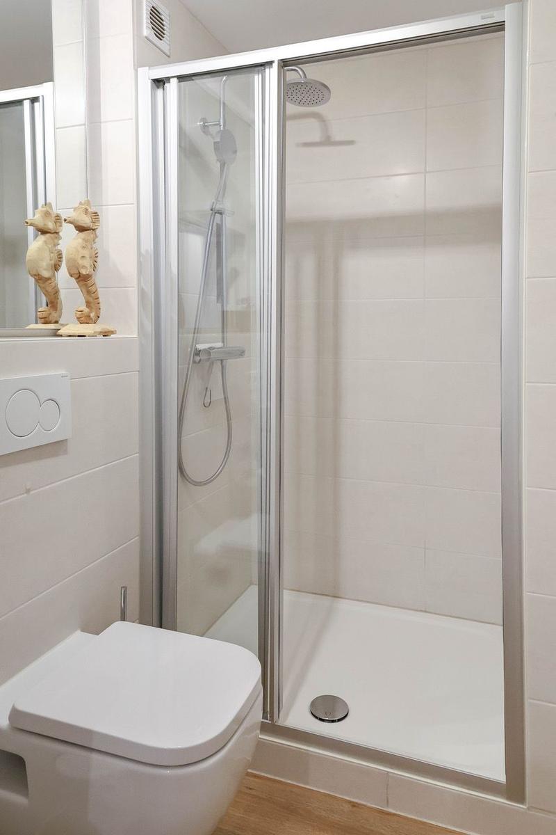 Duschkabine mit Duschbrause, Toilette und Meerespferd-Dekoration.