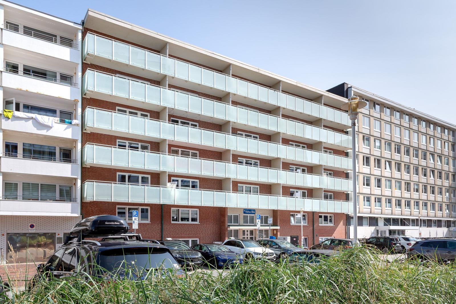 Mehrfamilienhaus mit Balkonen und Parkplatz vorne
