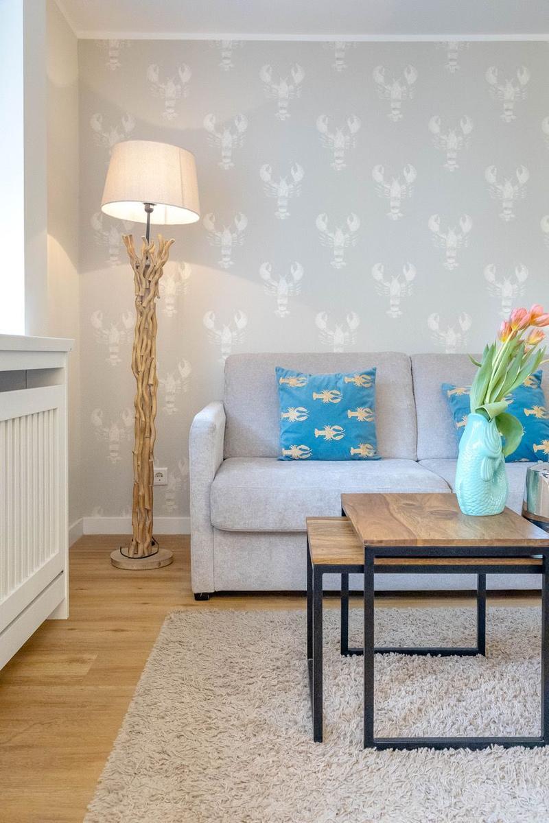 Ein Wohnzimmer mit grauem Sofa, blauen Kissen und einem Holztisch auf Teppichboden.