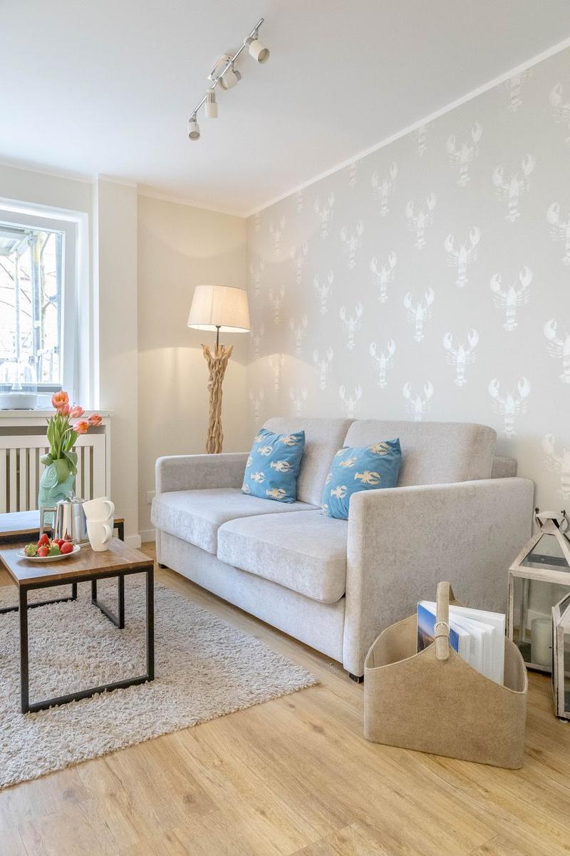 Wohnzimmer mit Sofa, Wand mit Hummermotiv, Tisch und Fenster