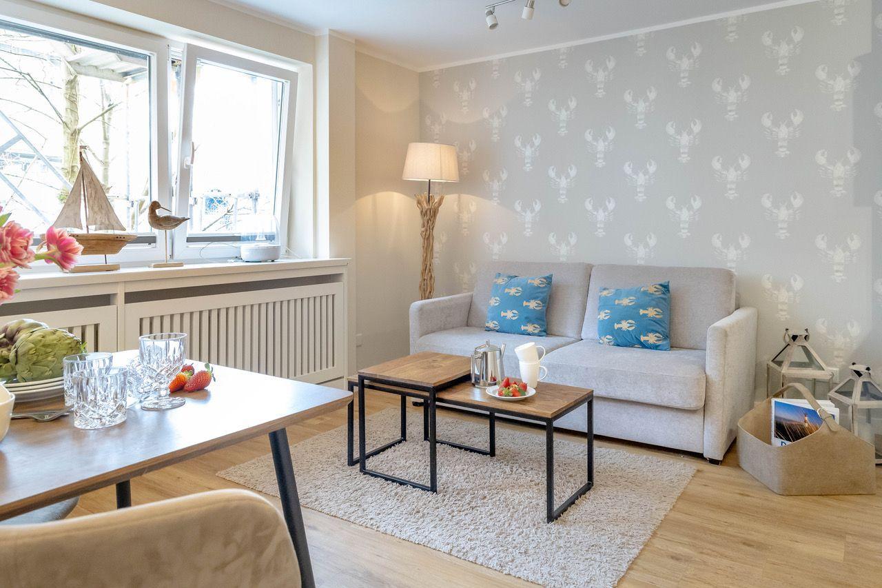 Wohnzimmer mit Sofa, Tisch und Fenster. Wandtapete mit Krebselementen.
