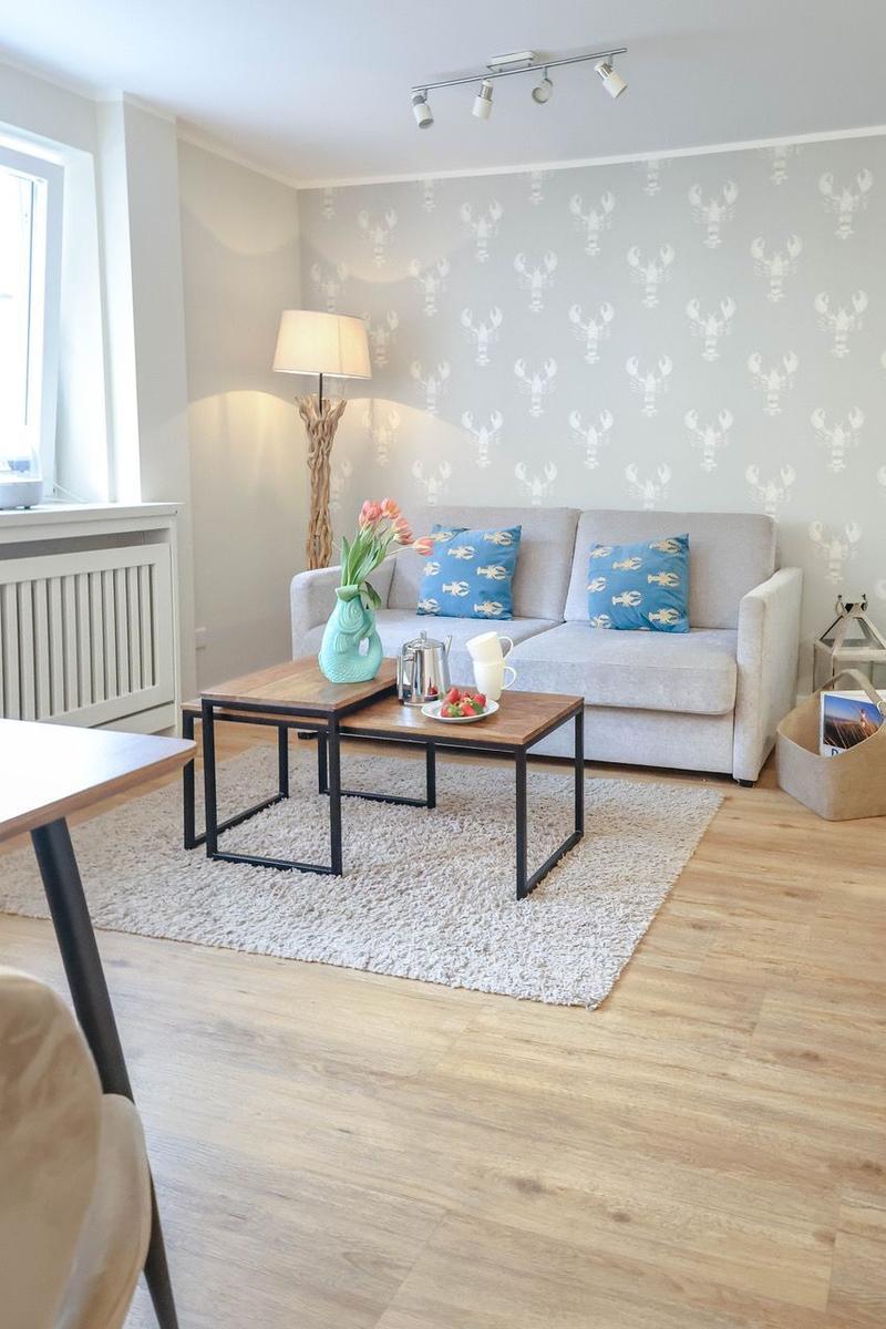 Wohnzimmer mit Sofa, Couchtisch und Tapete mit Krabbenmotiv.