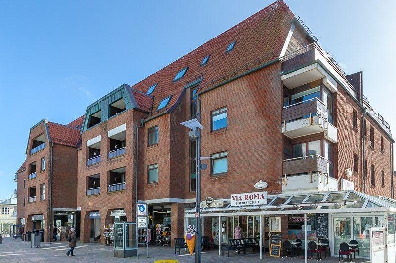 Rotes Backsteingebäude mit Balkonen und Geschäften im Erdgeschoss.