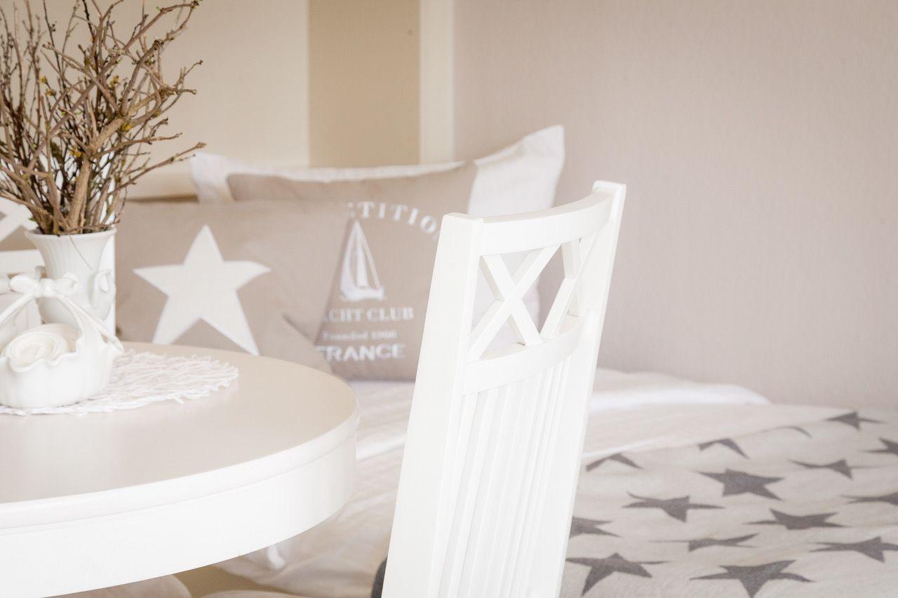 Weißer Tisch mit Stuhl und Bett mit Sternenmuster im Hintergrund.