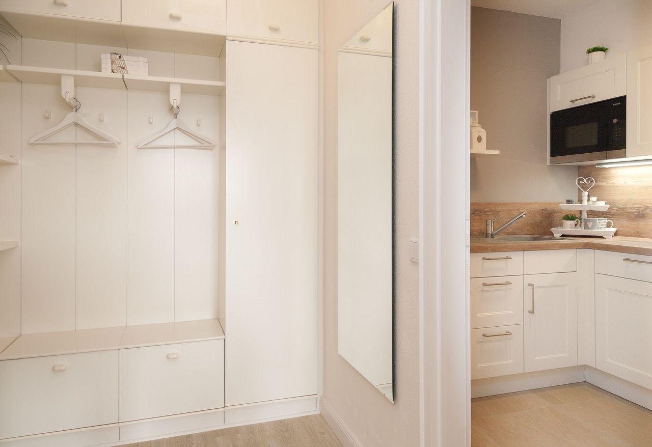 Schlafzimmer mit Kleiderschrank und Blick in die Küche mit Arbeitsplatte und Mikrowelle.