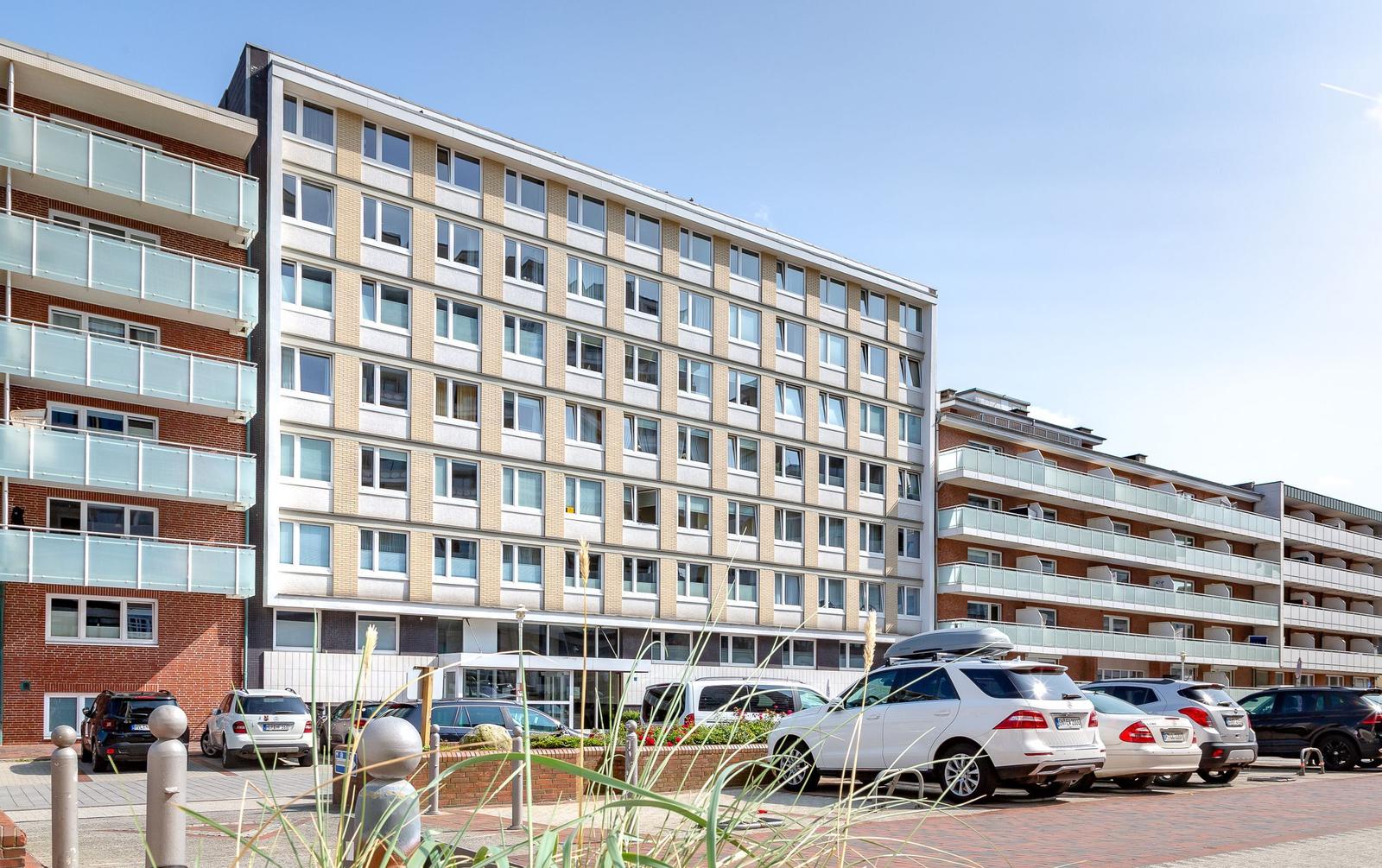 Modern apartment building with balconies and parking space in front.