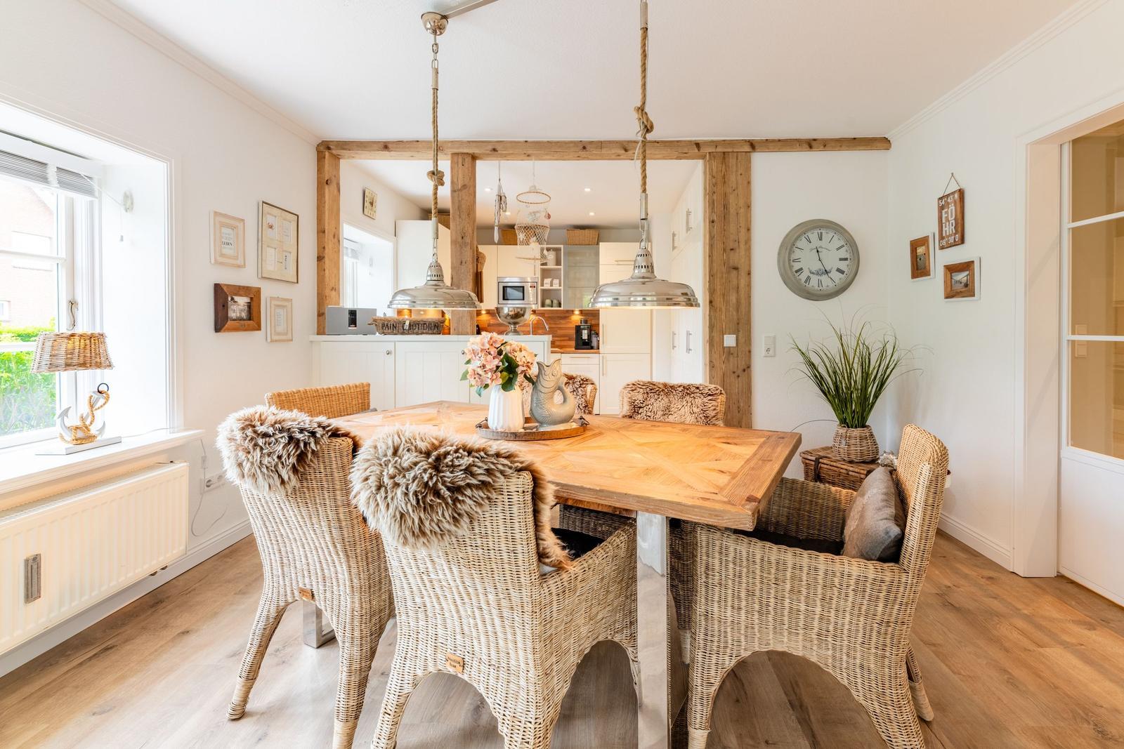 Esszimmer mit Holztisch, Rattanchairs und rustikalen Deckenbalken.