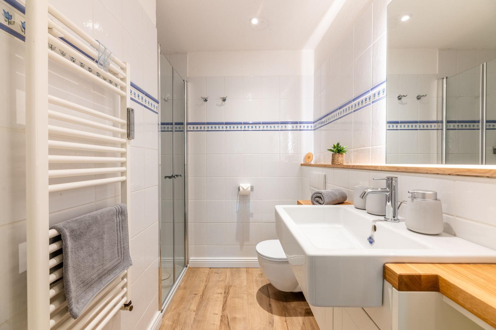 Badezimmer mit Dusche, Waschbecken und Heizkörper