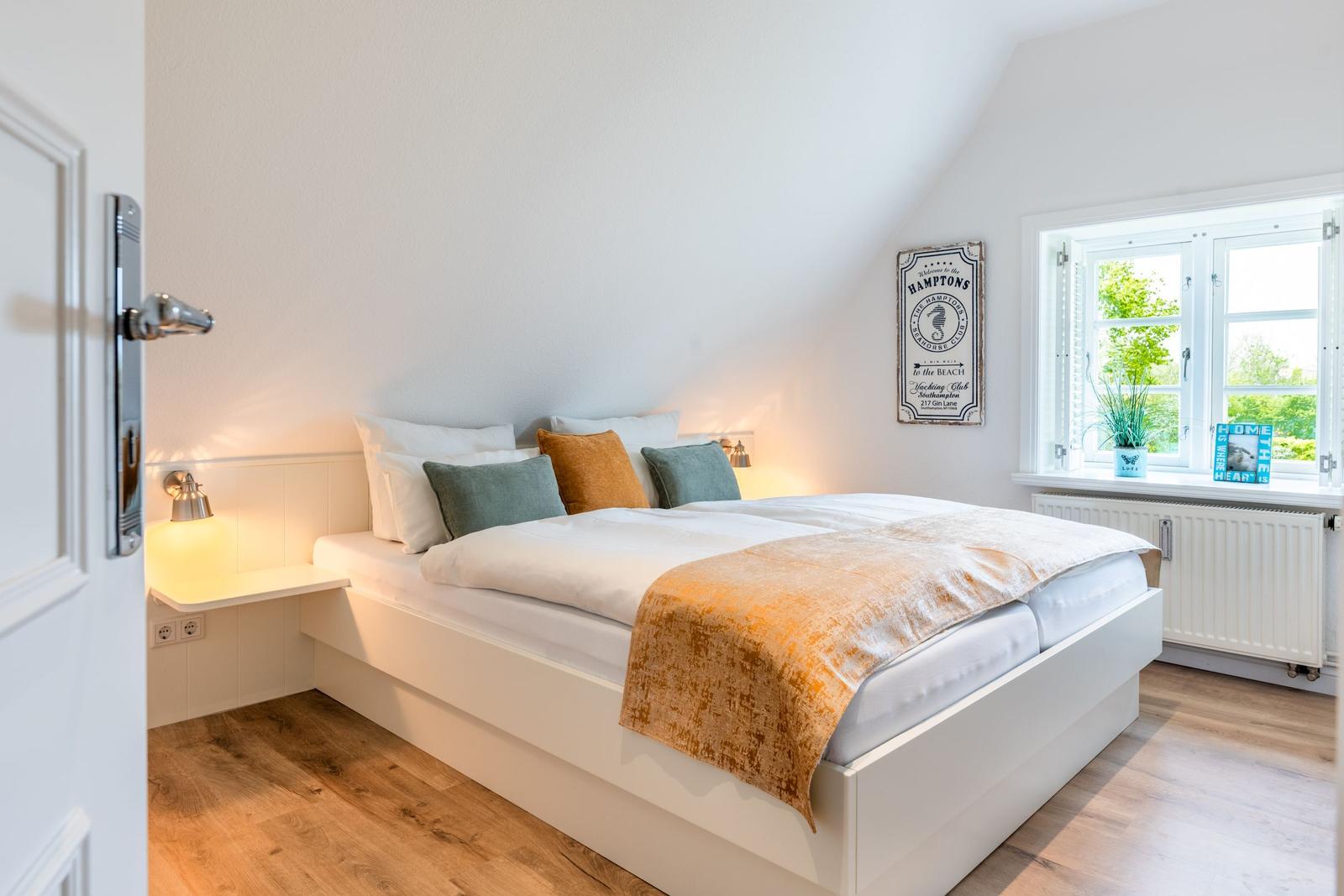 Schlafzimmer mit Doppelbett, Fenster und Wanddekoration.