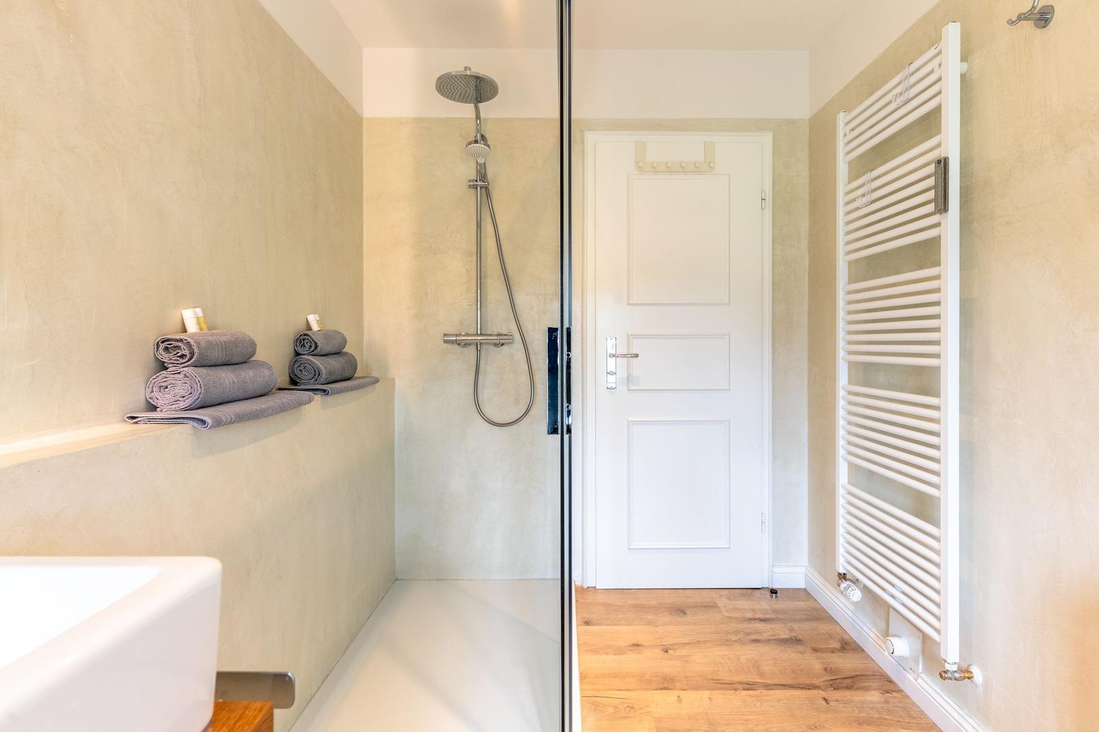 Badezimmer mit Dusche, Handtuchhalter und Heizkörper an der Wand.