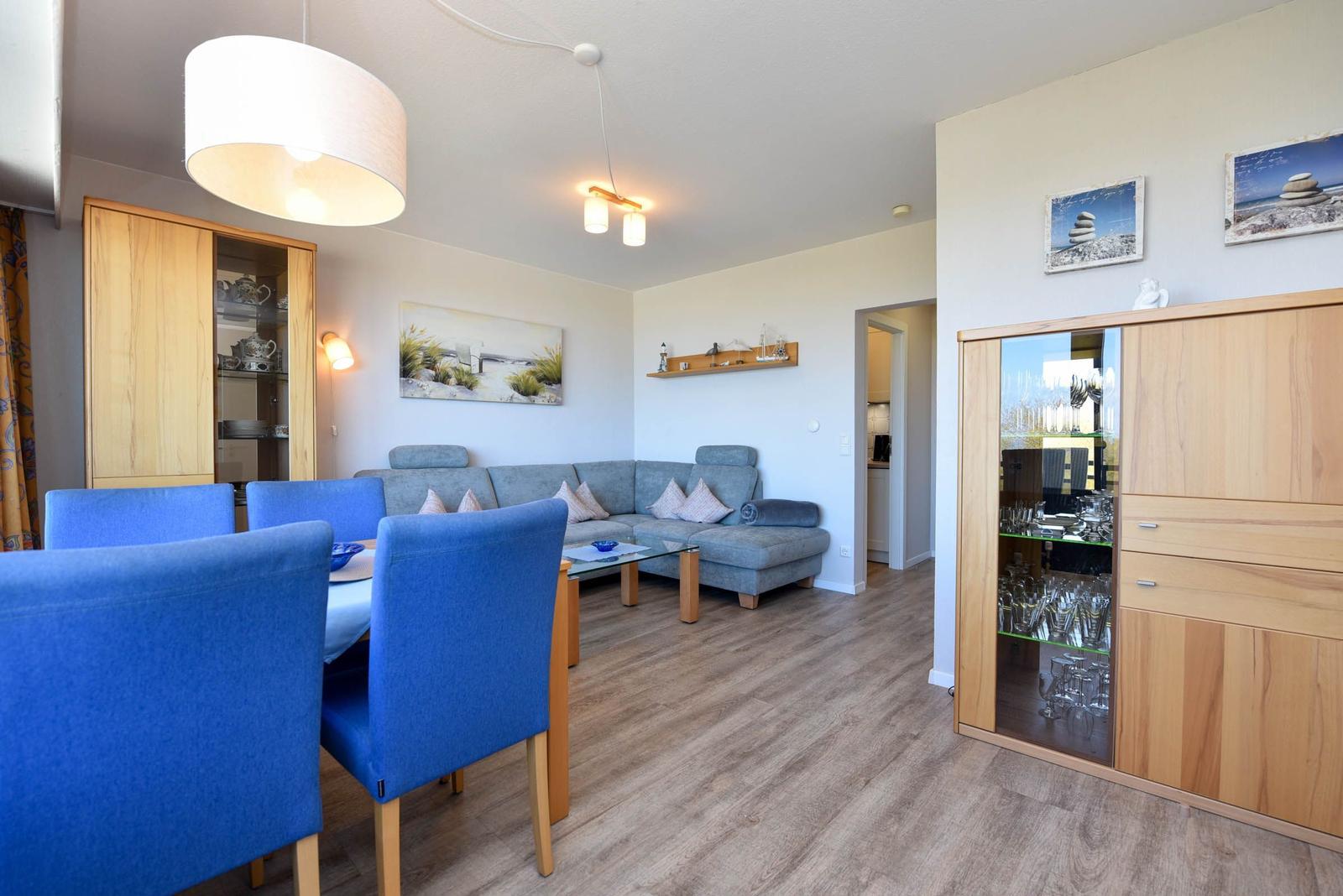 Wohn- und Essbereich mit blauen Stühlen, Sofa und Holzmöbeln.