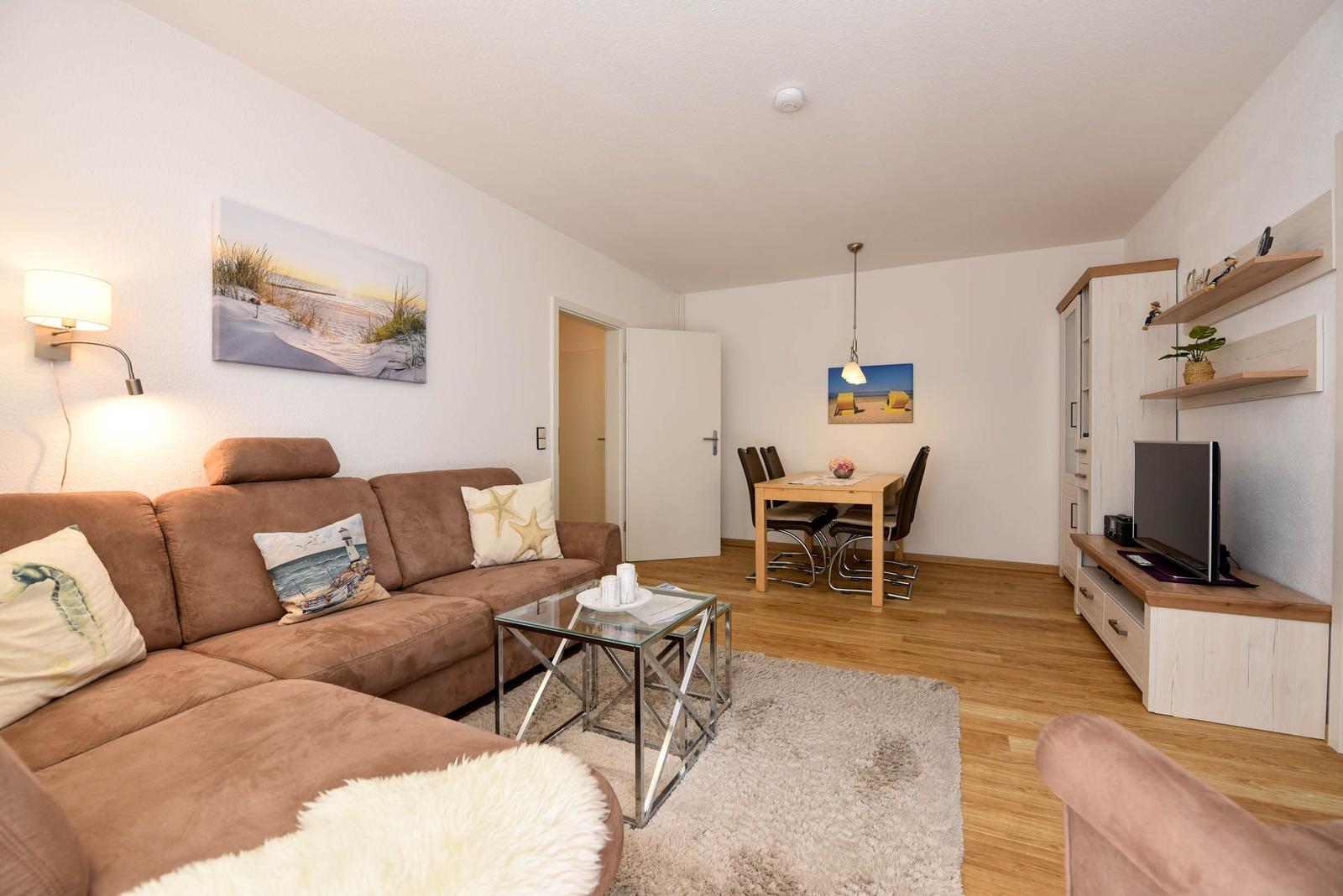 Wohn- und Essbereich mit Sofa, Esstisch und Fernseher.