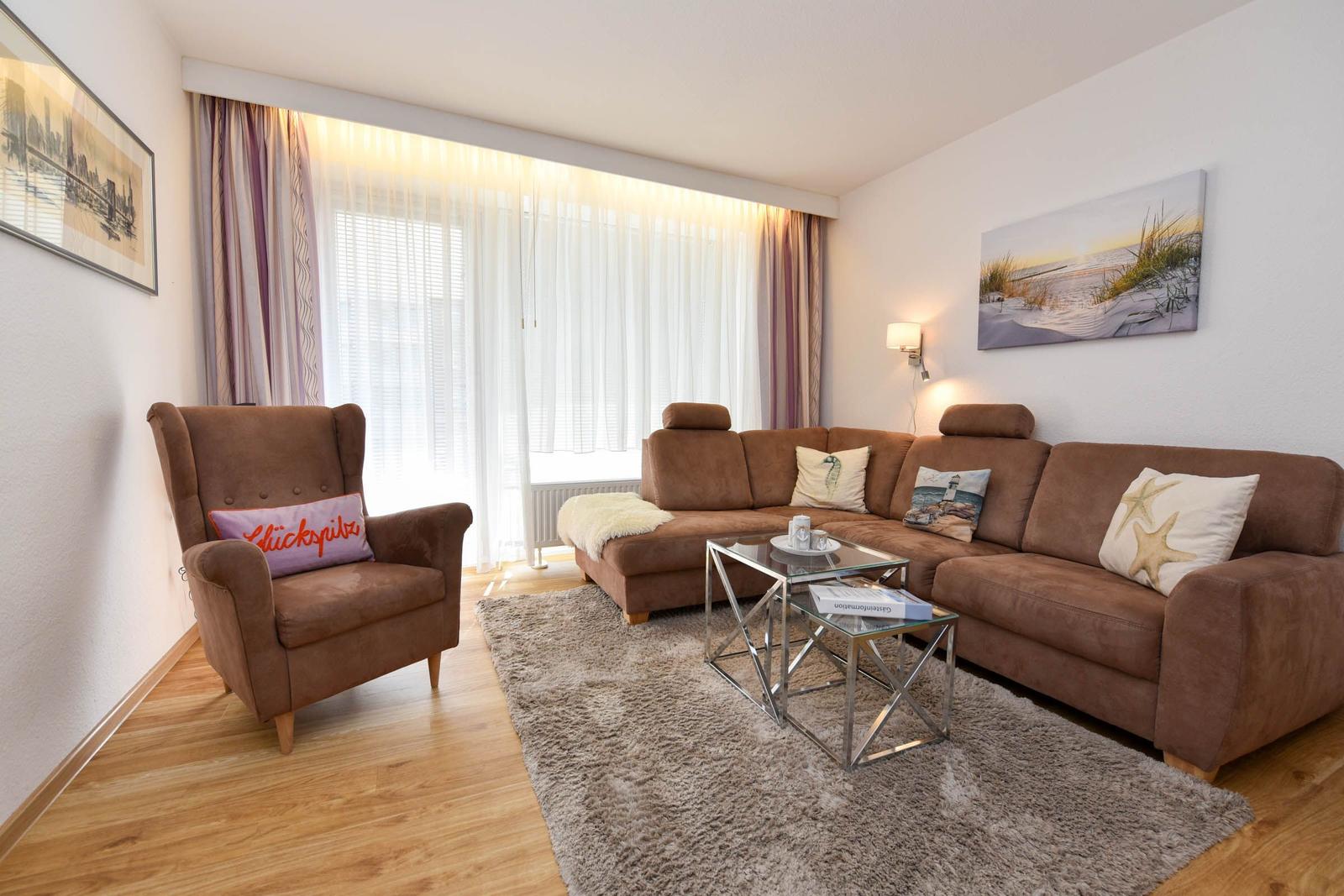 Wohnzimmer mit braunem Sofa, Sessel und Glas-Tisch auf Teppich