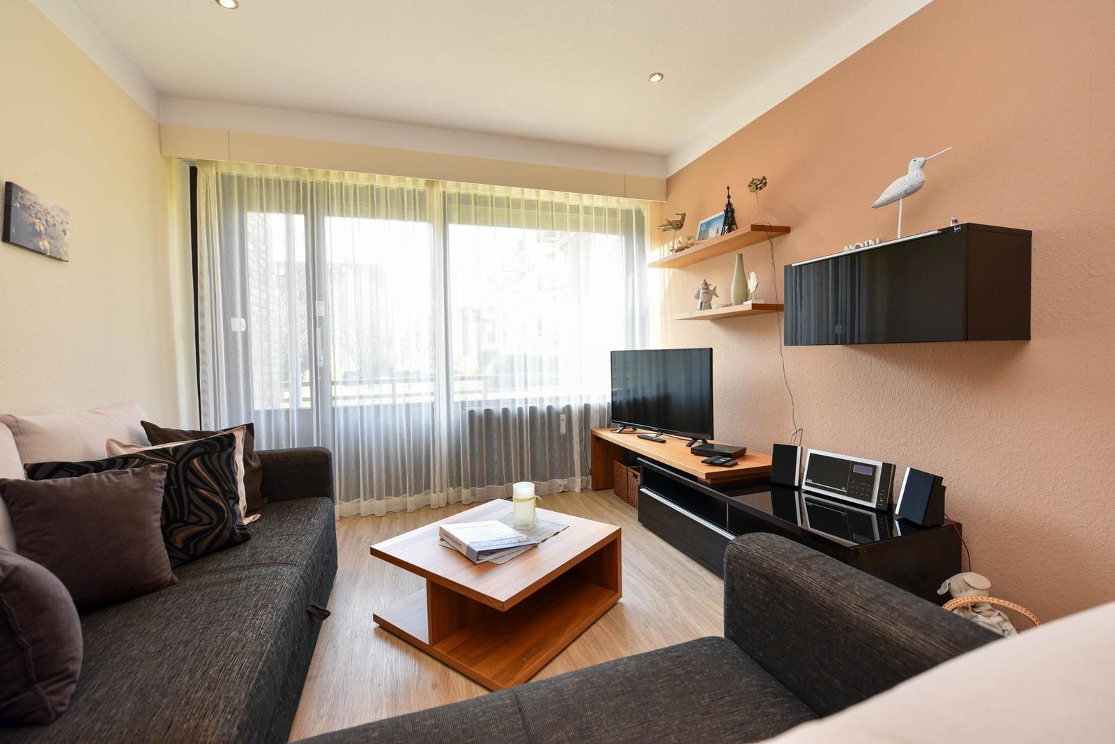 Wohnzimmer mit Sofa, Couchtisch und Fernseher an der Wand.