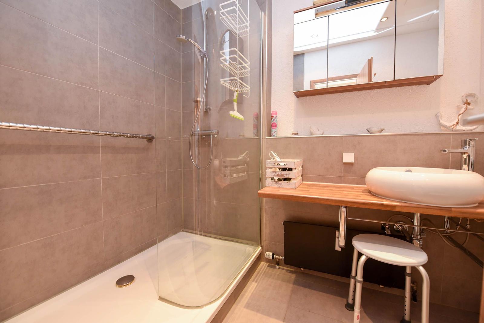 Dusche mit Duschbrause, Waschbecken und Spiegelschrank.