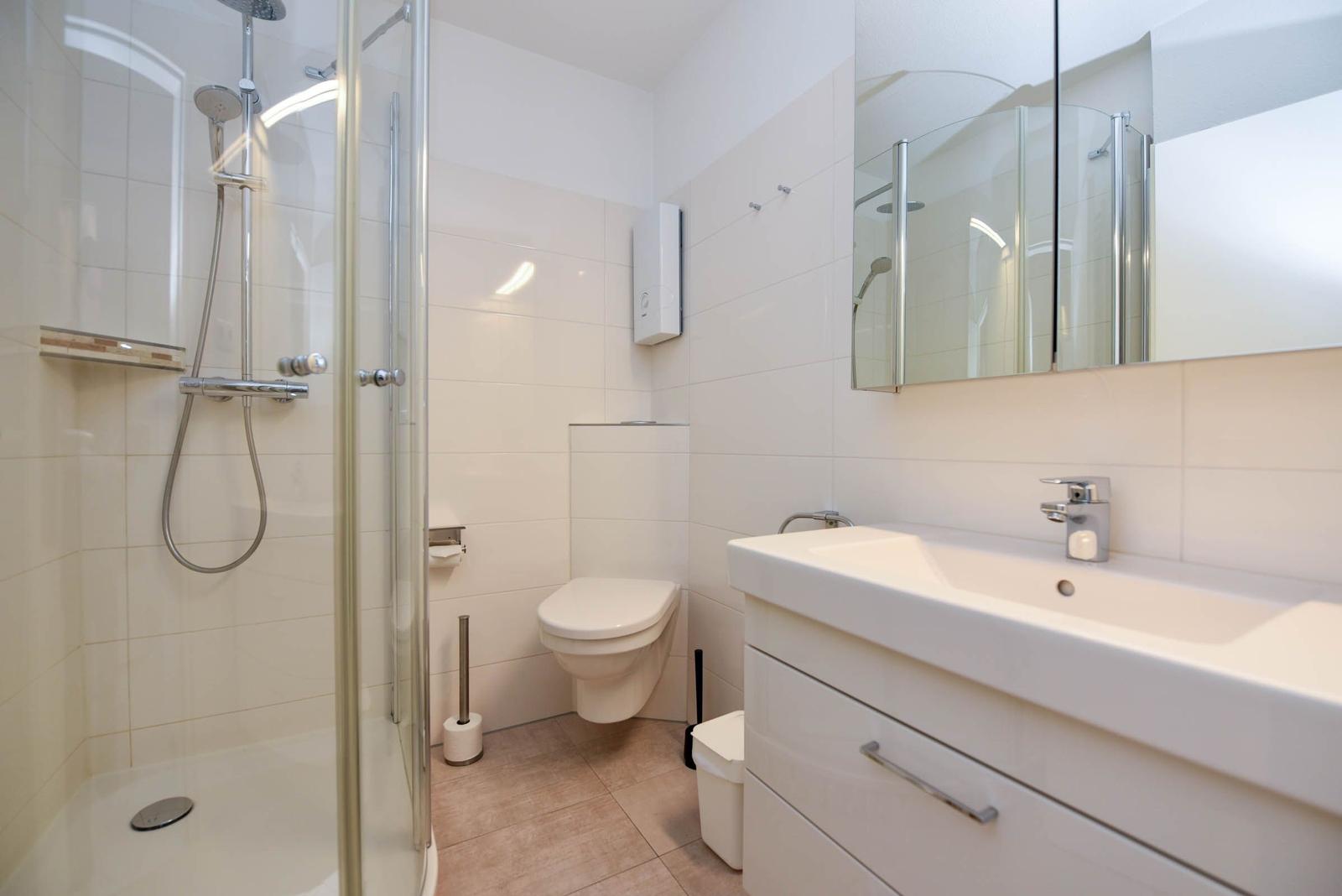 Badezimmer mit Dusche, Toilette und Waschbecken.
