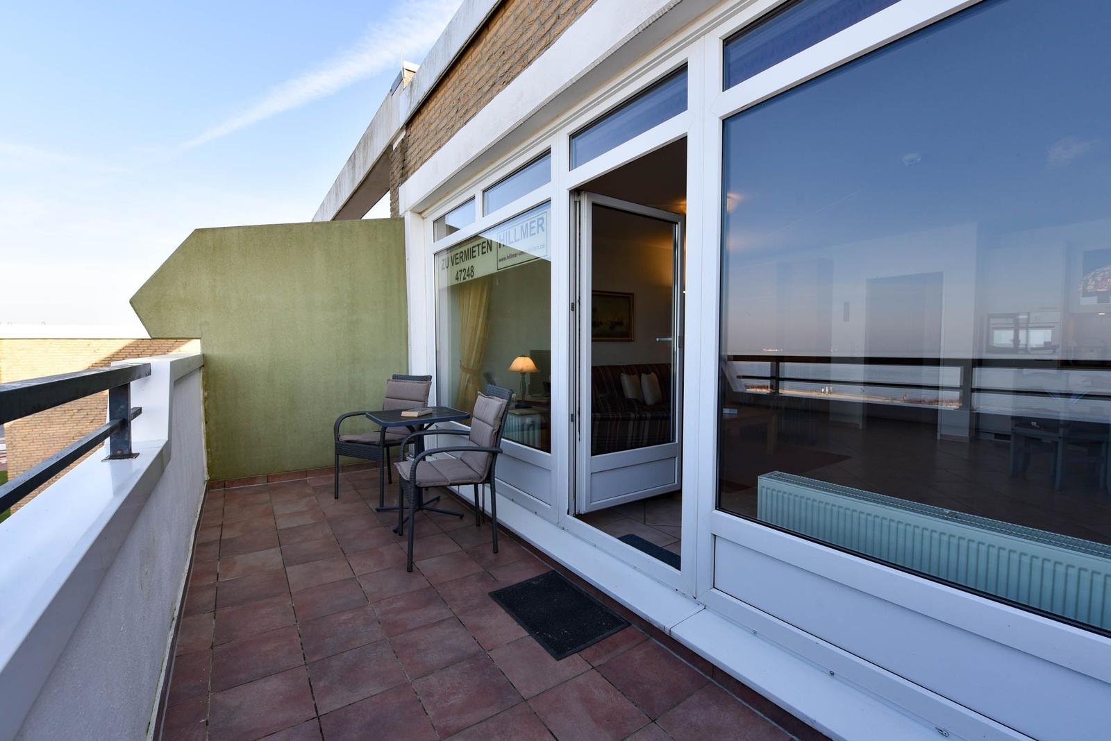 Terrasse mit Tisch und Stühlen, Blick in Wohnbereich mit Sofa.