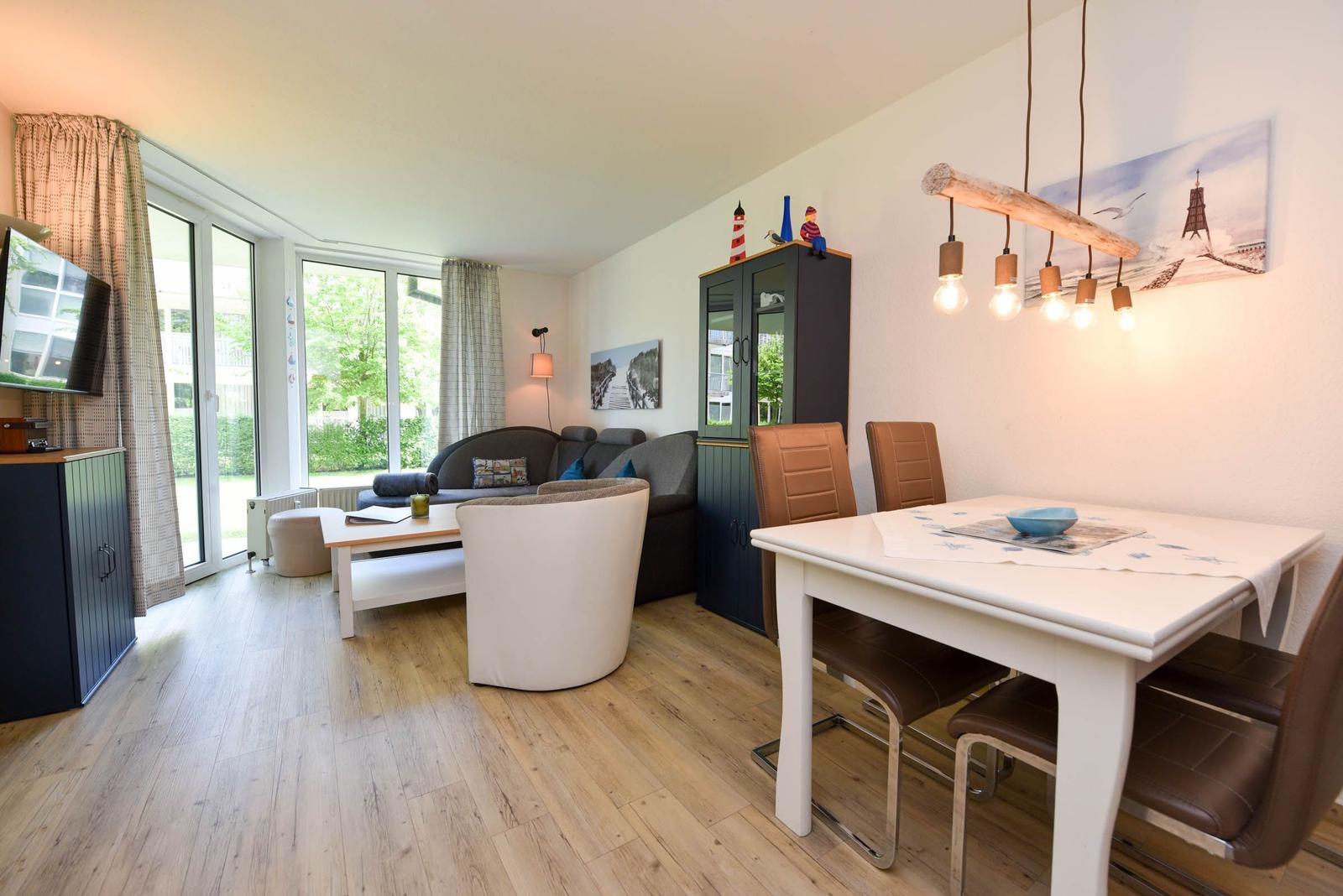 Wohn- und Essbereich mit Holzboden, Sofa, Esstisch und Fenster zur Terrasse.