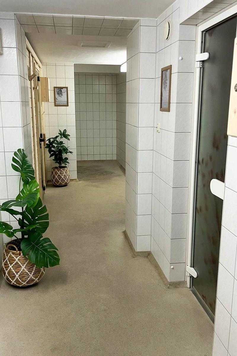 Hallway with white tiles, plants, and doors