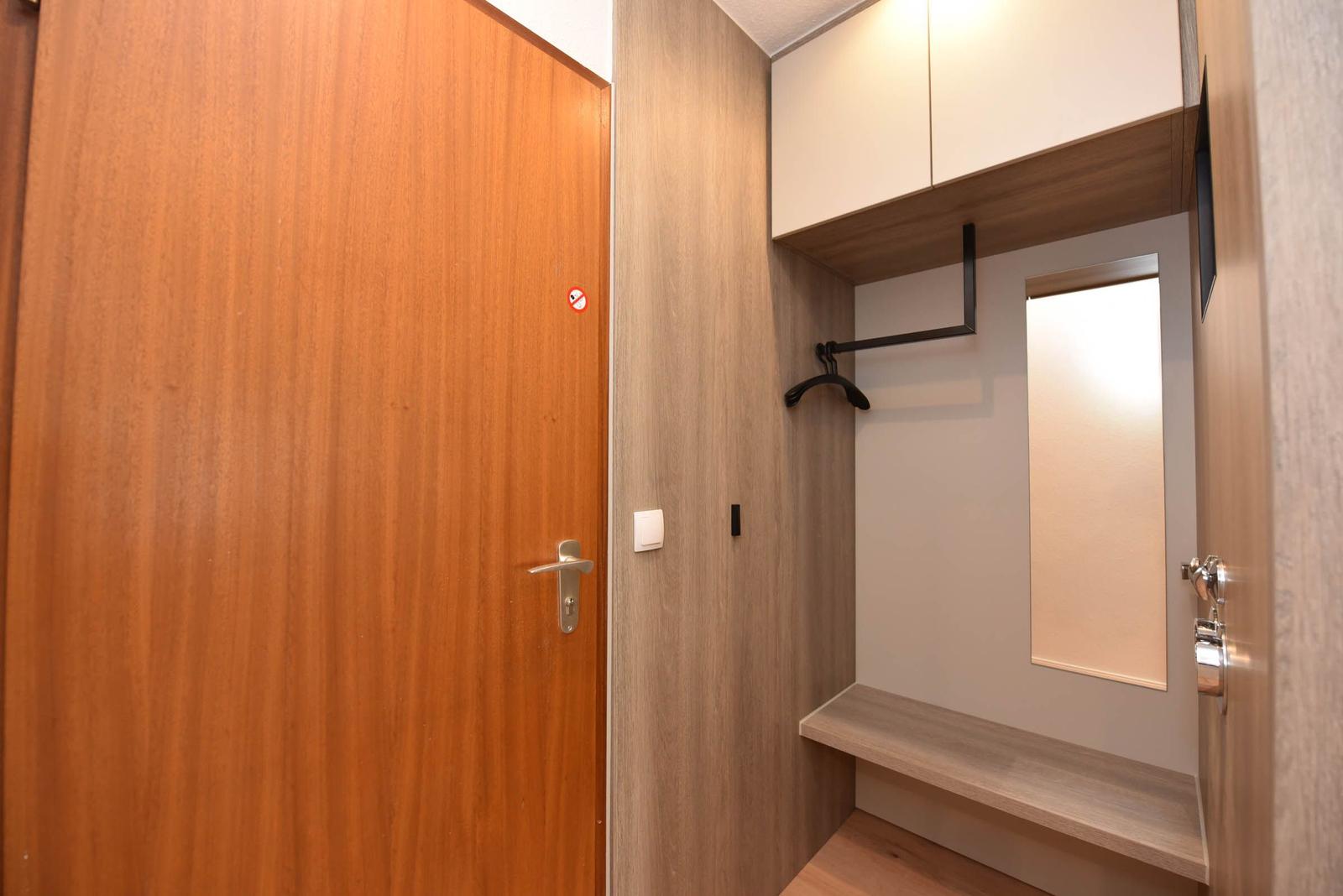 Schlafzimmer mit Kleiderschrank, Spiegel und Sitzbank.