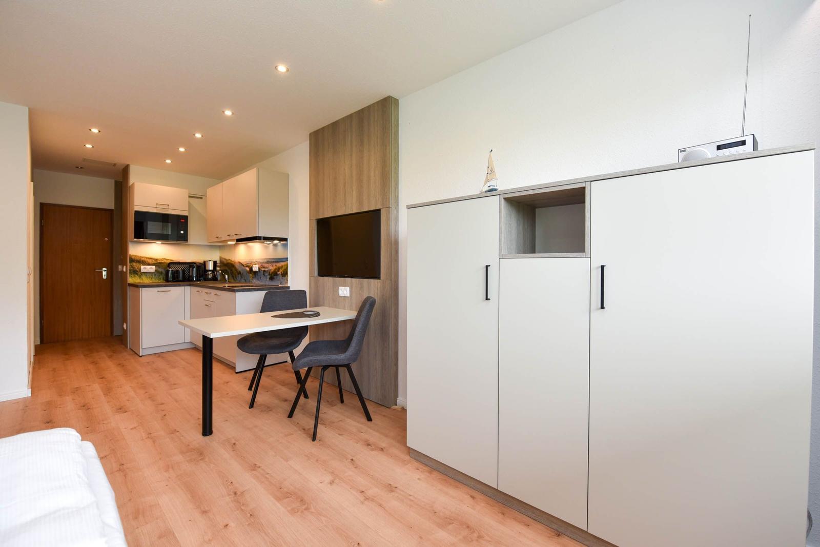 Küche mit Essbereich, Schlafzimmer und Schrank mit Fernseher.