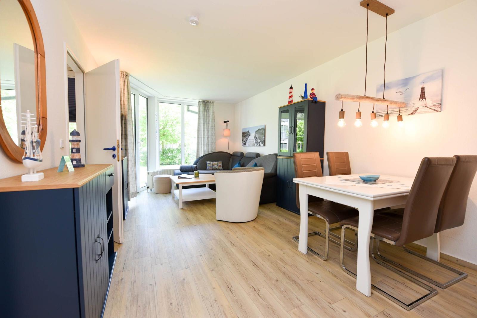Wohn- und Essbereich mit Holzboden, Esstisch und Sofa. Dekoration mit Leuchten und Bildern.