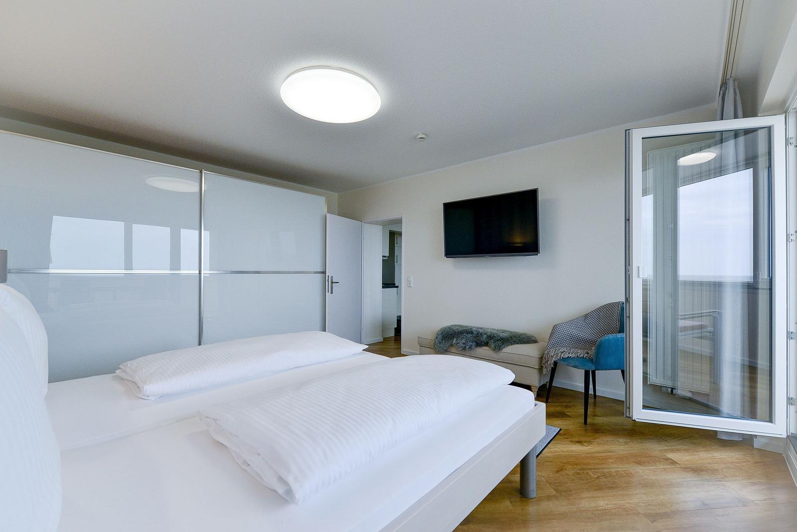 Bedroom with double bed, TV, and balcony door.
