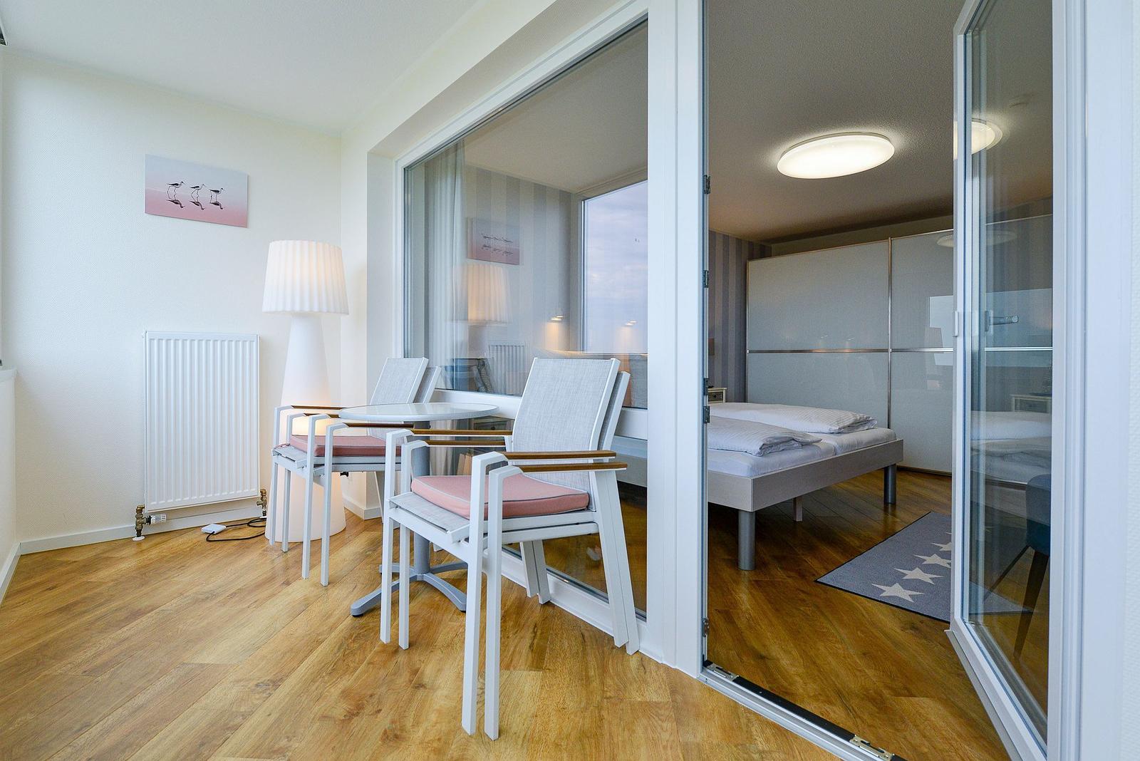 Living area with dining table and bedroom with bed and wardrobe.