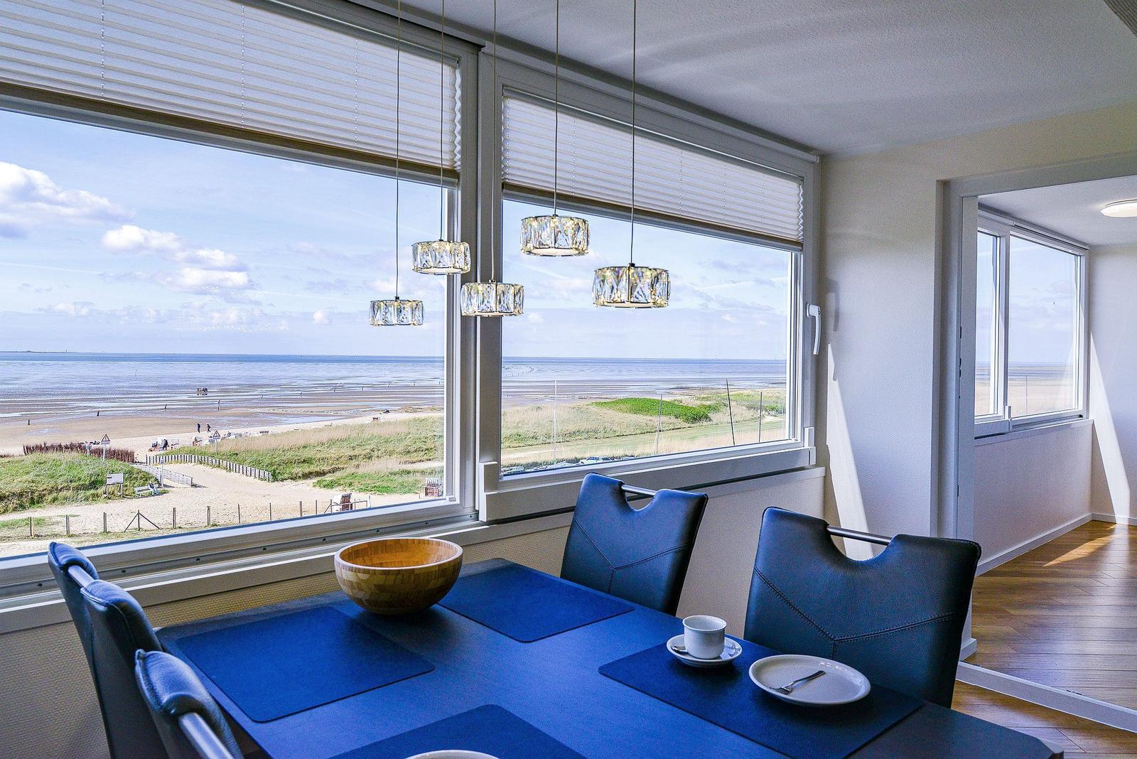 Dining room with sea and beach view. Table with chairs and pendant lights.