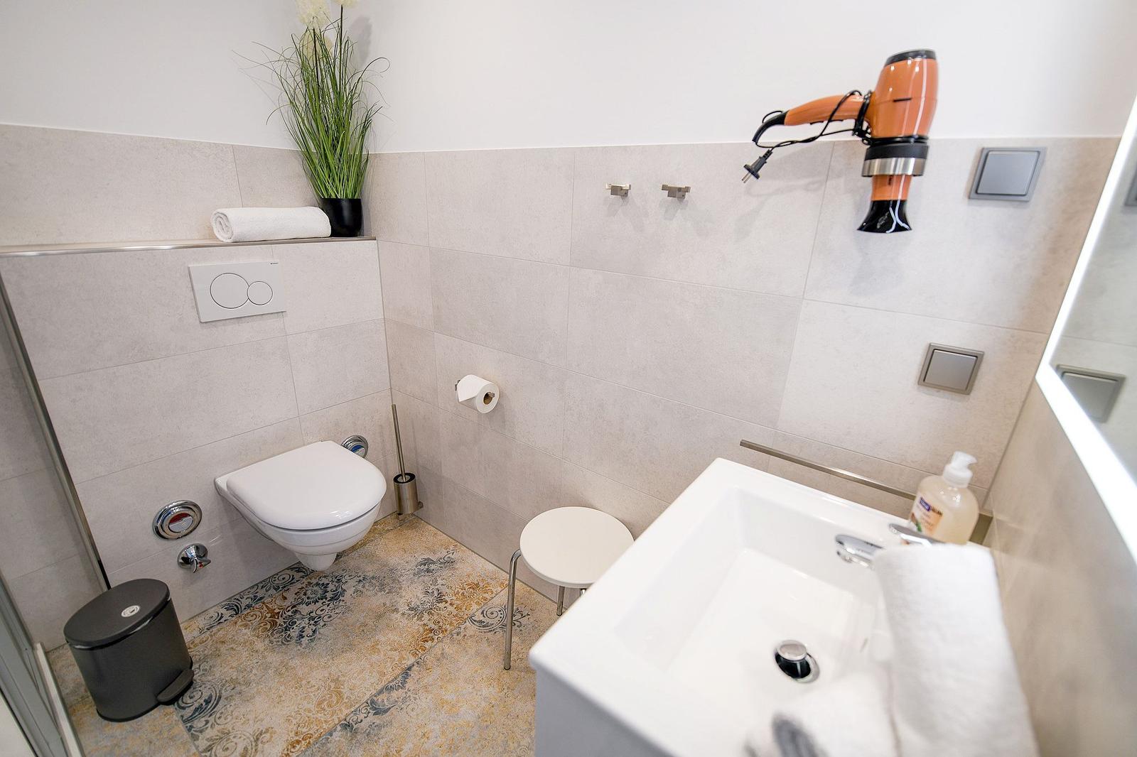 Badezimmer mit Toilette, Waschbecken und Haartrockner an der Wand.
