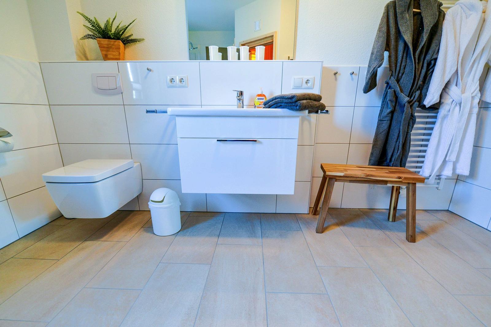 Badezimmer mit Toilette, Waschbecken und Bademanteln.