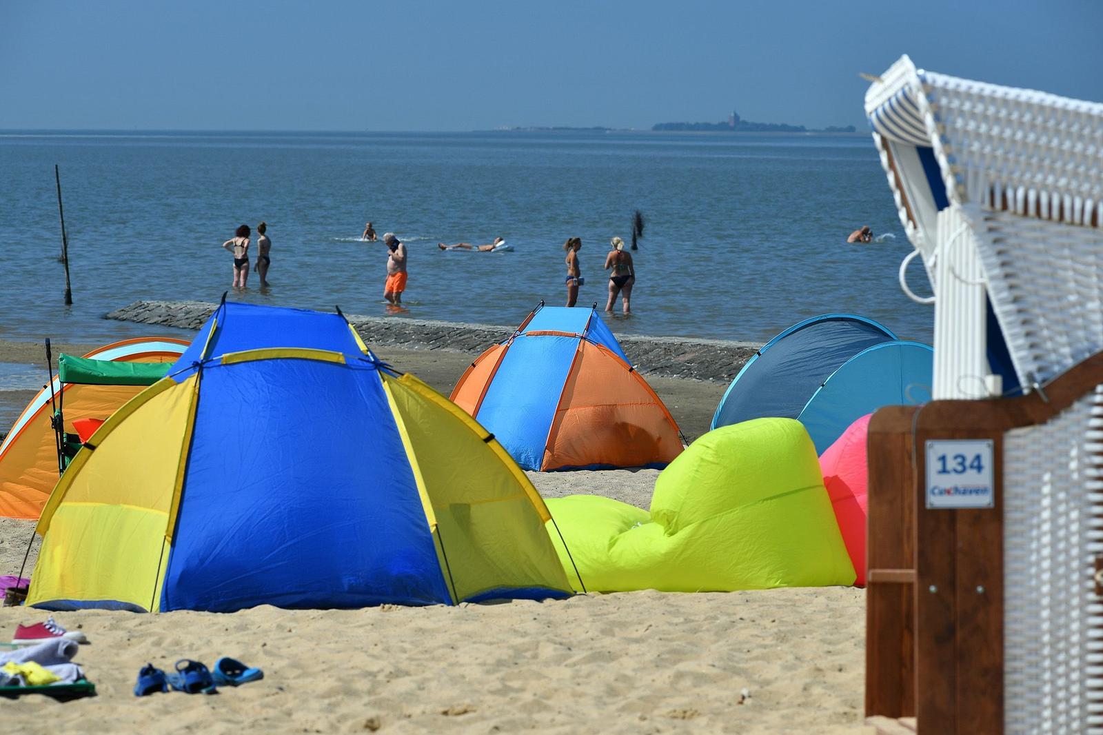 Strand mit bunten Strandzelten und Badegästen im Hintergrund. Strandkorb mit Nummer 134.