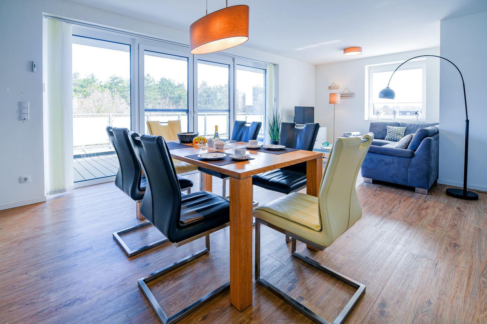 Essbereich mit Tisch und Stühlen. Wohnbereich mit Sofa und Balkon.