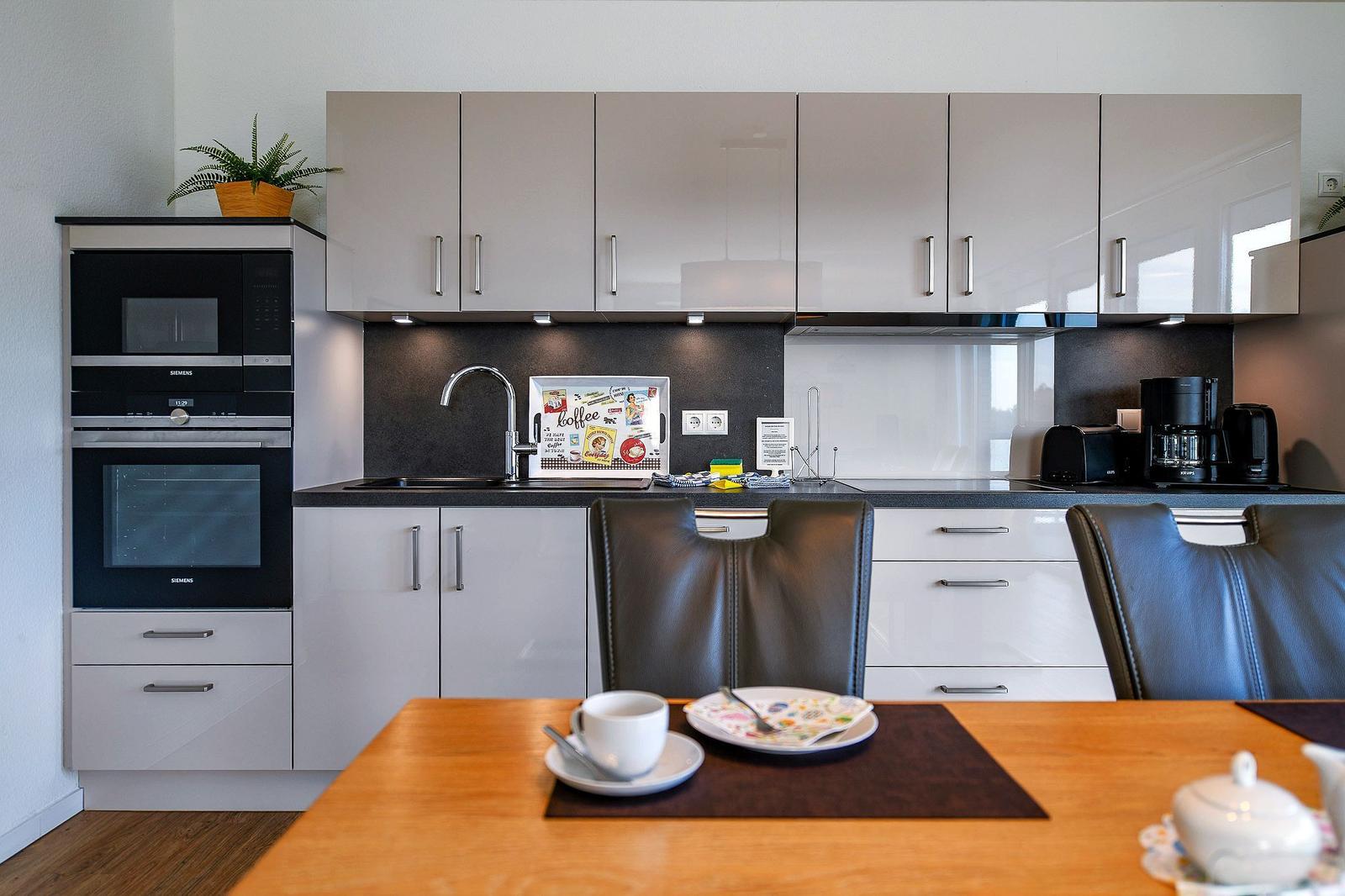 Moderne Küche mit Essbereich, Edelstahlspüle und integriertem Backofen.