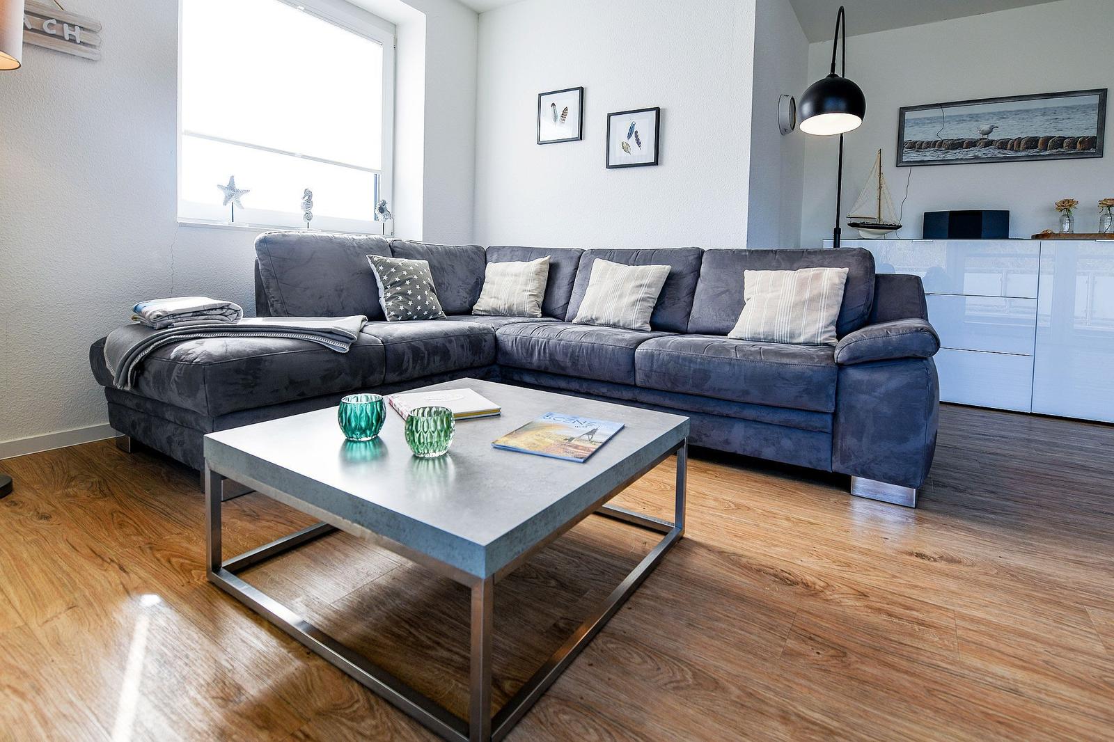 Ein Wohnzimmer mit grauem Sofa, Holzboden und modernem Couchtisch.