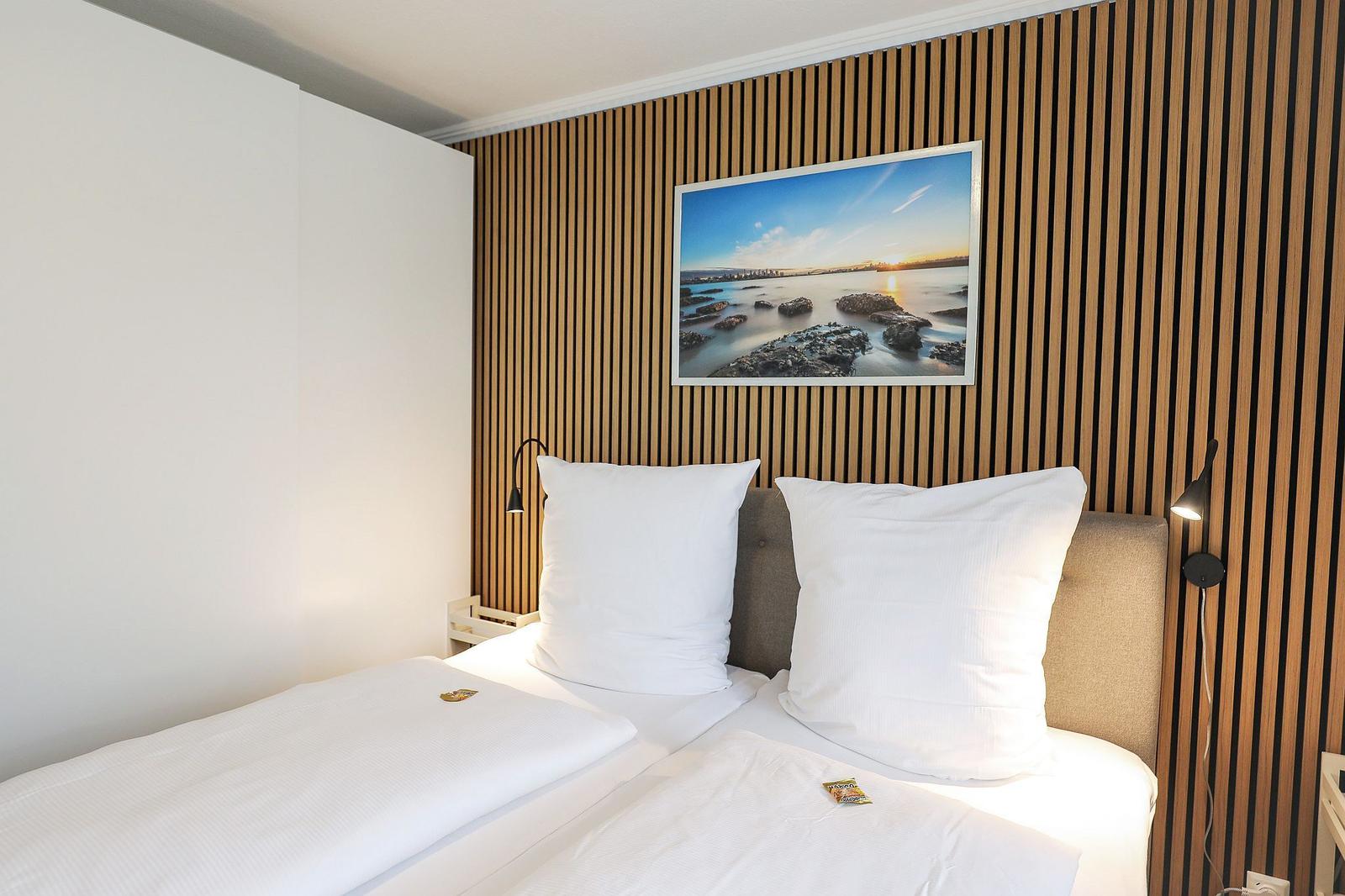 Schlafzimmer mit Bett, Holzwand und Bild an der Wand.