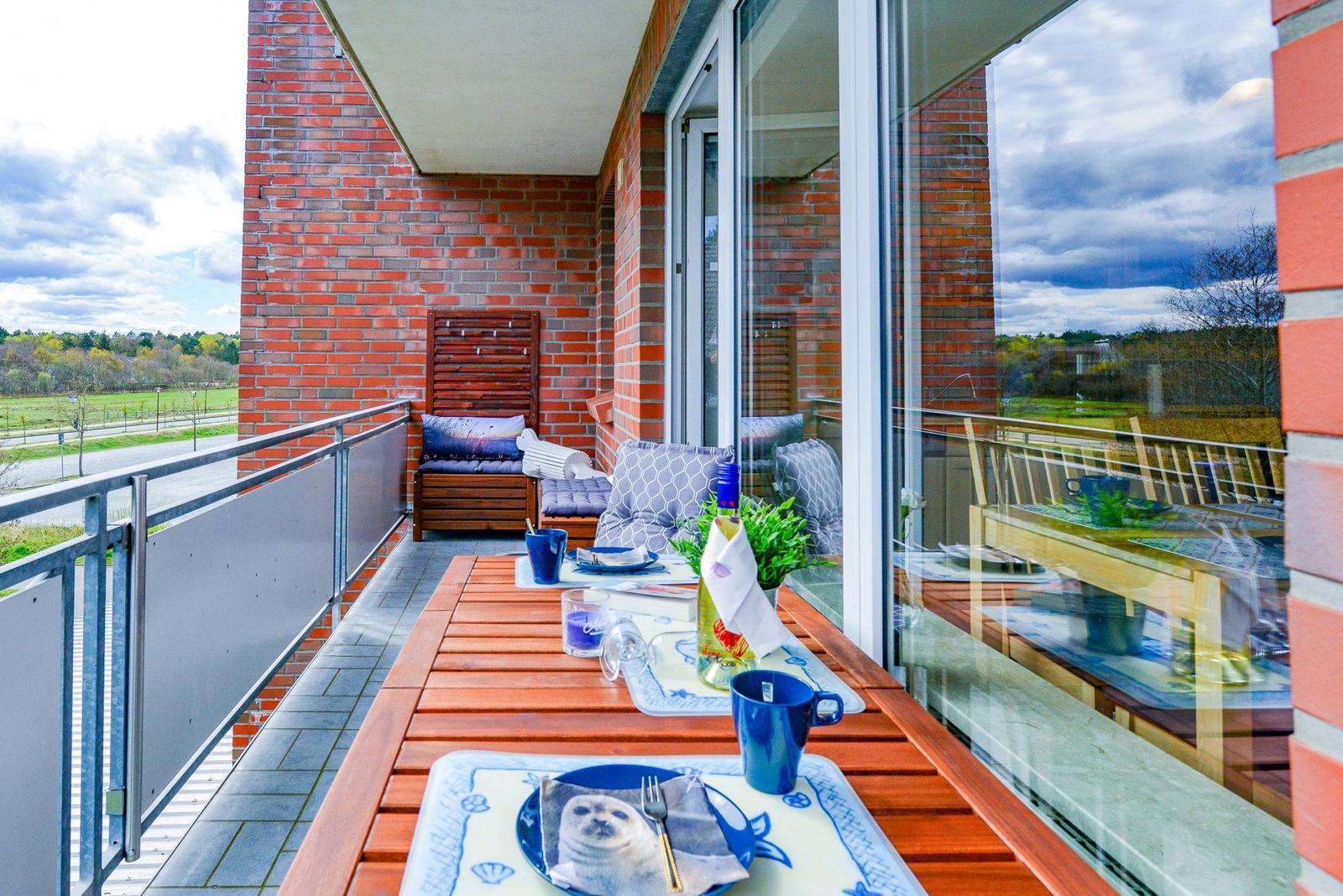 Terrasse mit Tisch, Stühlen und Blick auf Felder.