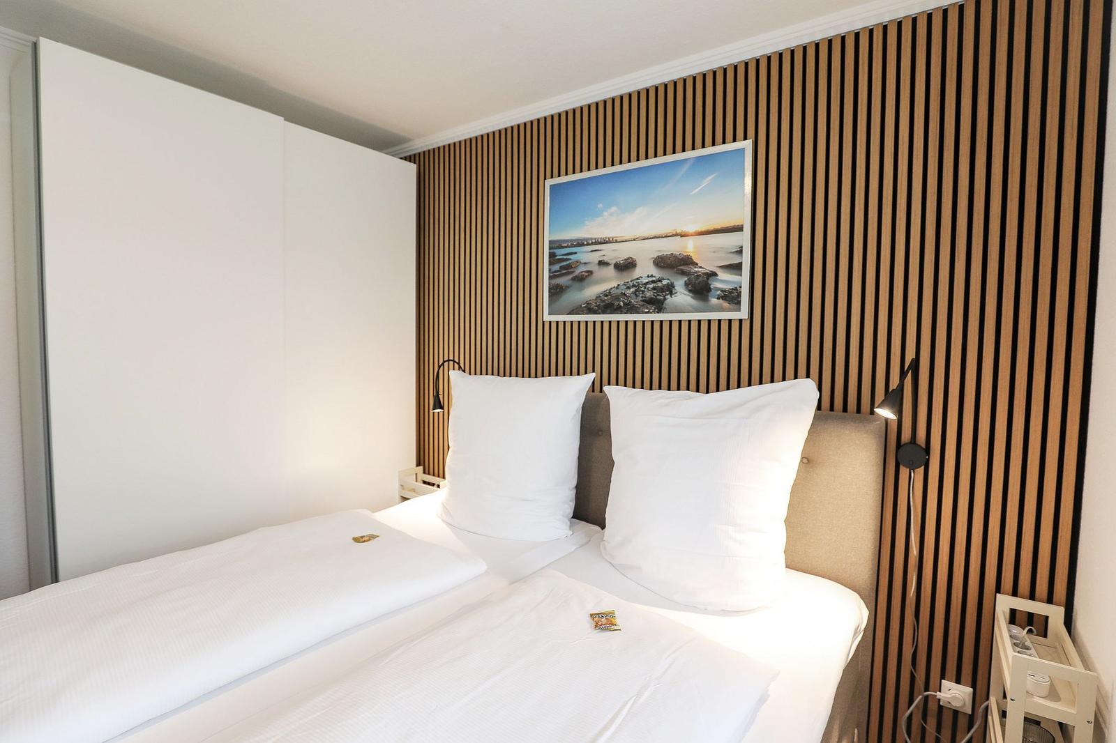 Schlafzimmer mit Bett, Holzwand und Bild an der Wand.