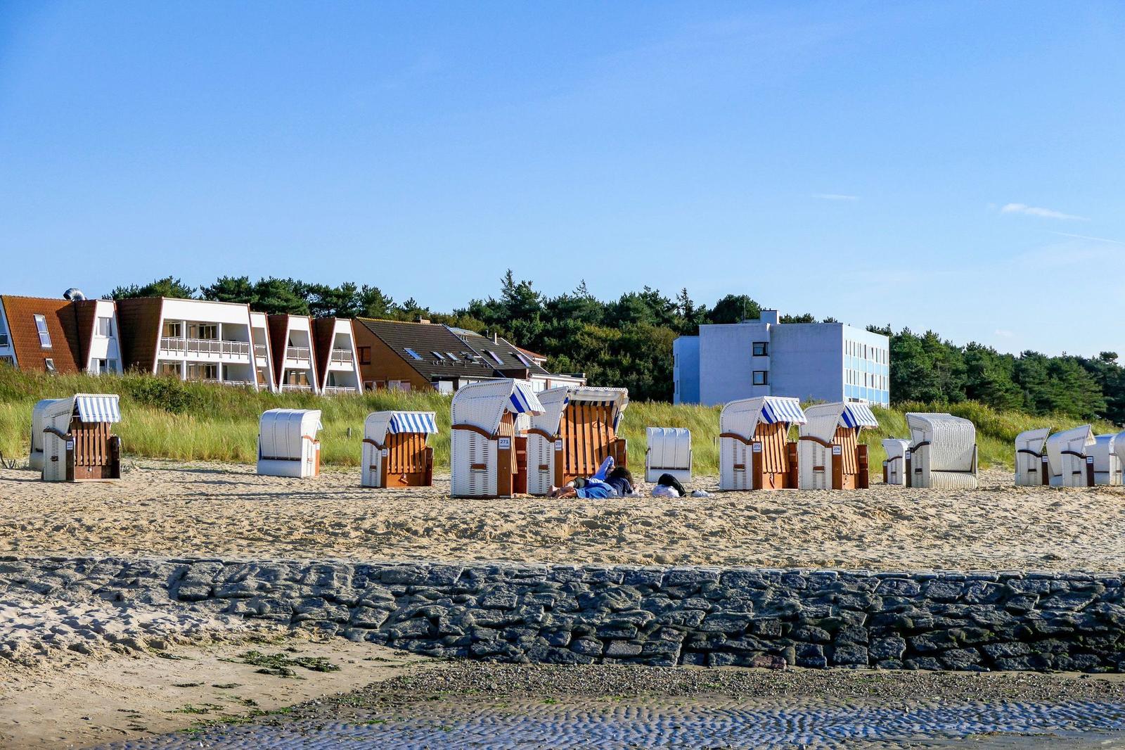 Beach with beach chairs, stone protection, and vacation homes in the background.