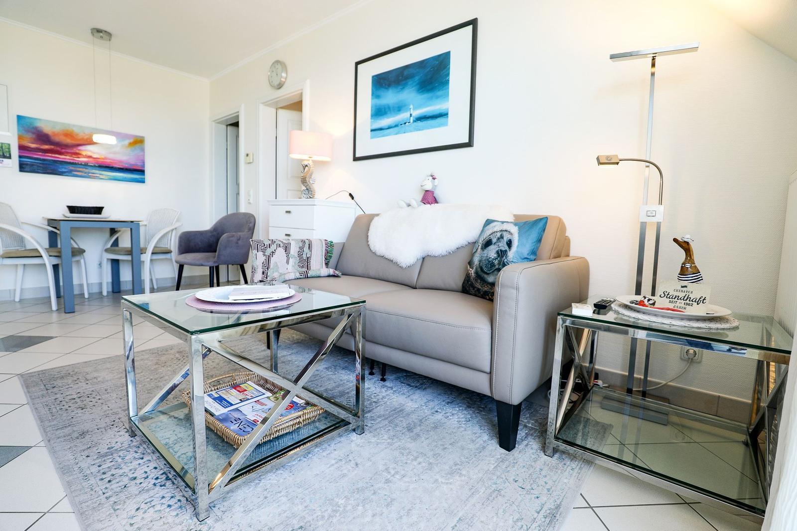 Living room with sofa, glass table, and wall art.