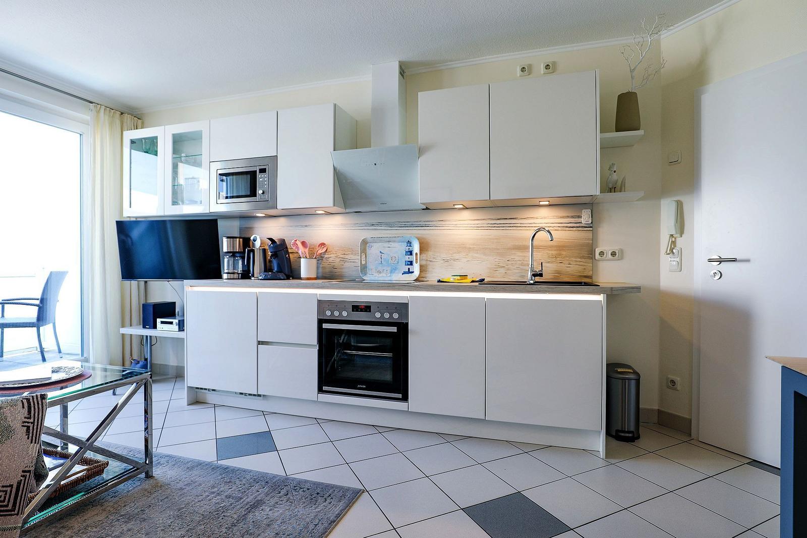 Kitchen with white cabinets, sink, and oven. Terrace with seating area.