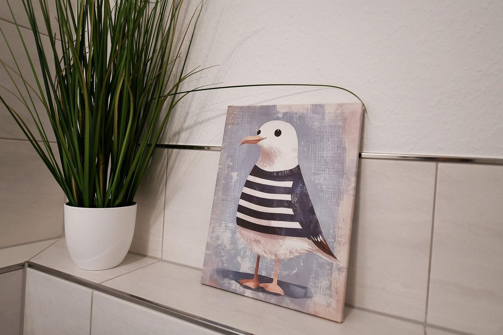 Ein Bild mit einer Möwe in gestreiftem Oberteil steht neben einer Pflanze auf einer Fliese.