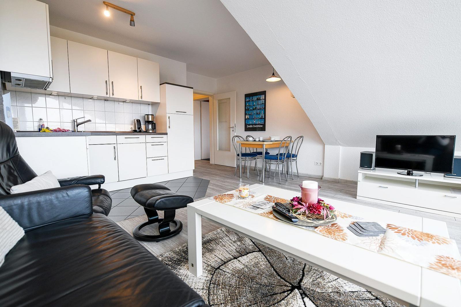 Wohnung mit Küche, Essbereich und Wohnzimmer mit Fernseher und Sofa.