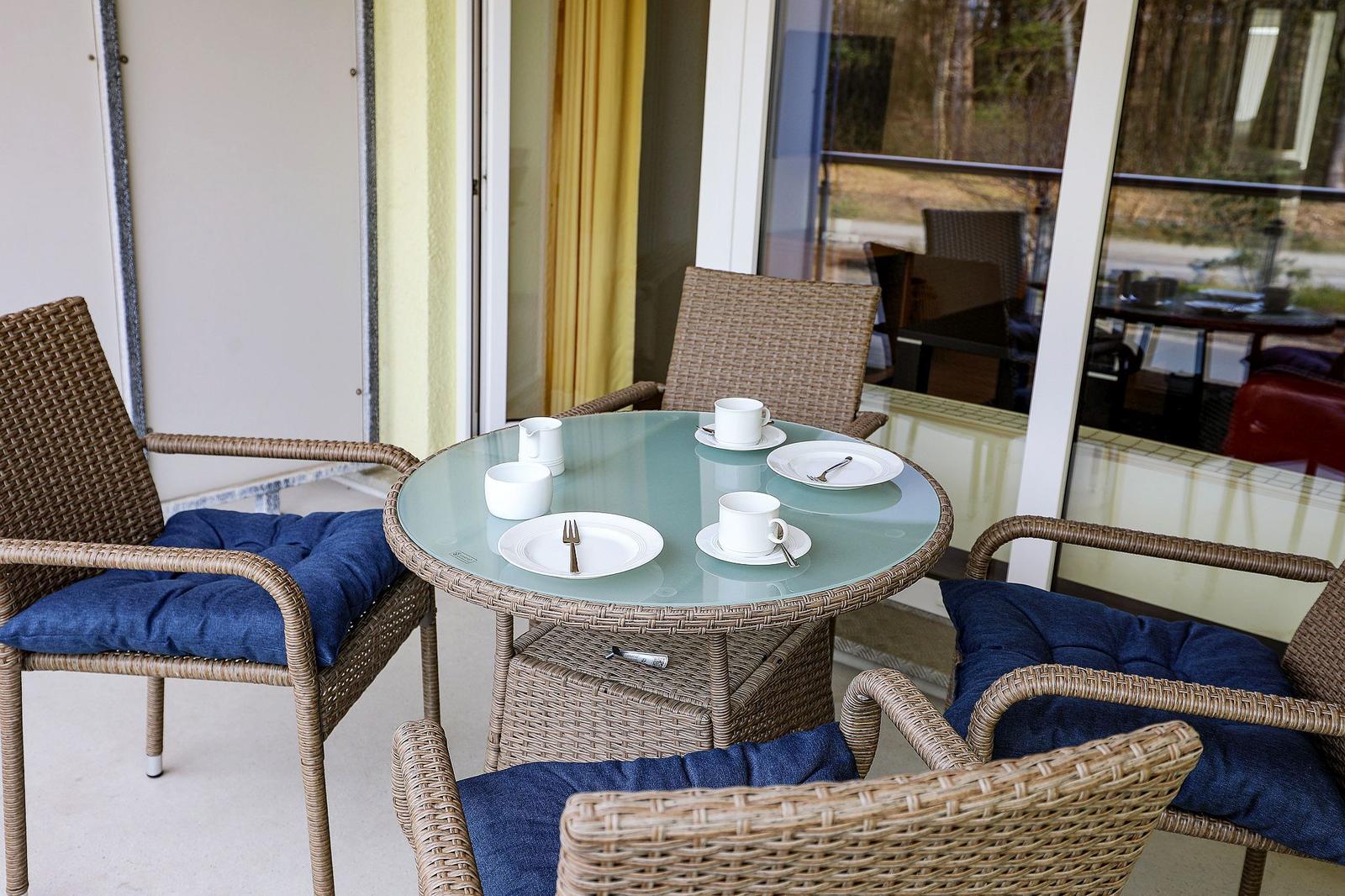 Rundtisch mit vier Stühlen und blauen Kissen auf einer Terrasse.